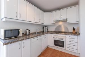 a kitchen with white cabinets and a microwave at Penthouse with a fantastic view in La Cala de Mijas