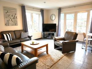 a living room with leather couches and a tv at Villa Lachmöwe in Sint Maartensvlotbrug