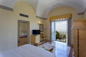 a bedroom with a bed and a television and a balcony at Villa Tuscolana in Frascati
