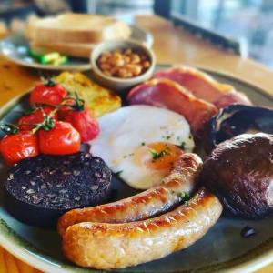 a plate of breakfast food with eggs sausage and tomatoes at Beach Seaside Apartment sleeps 4 Lytham St Annes in Lytham St Annes