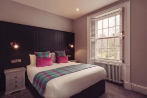 1 dormitorio con 1 cama grande con almohadas rosas y verdes en Tweedies Bar and Lodge, en Grasmere