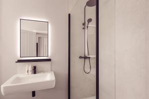 W łazience znajduje się umywalka oraz prysznic z lustrem. w obiekcie Tweedies Bar and Lodge w mieście Grasmere