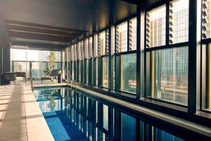 a swimming pool in the middle of a building with windows at Quincy Hotel Melbourne in Melbourne