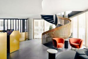 a lobby with orange chairs and a staircase at Quincy Hotel Melbourne in Melbourne