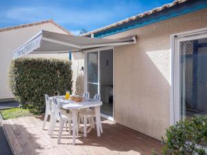 une table et des chaises blanches avec un parasol blanc dans l'établissement Vacancéole - les villas du lac, à Soustons