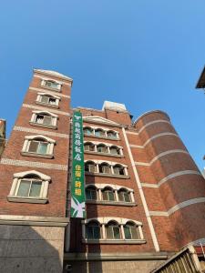 a red brick building with a green sign on it at Duke Business Hotel in Taoyuan