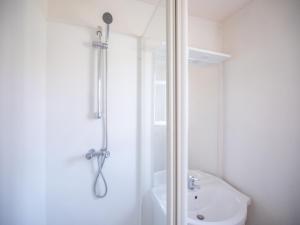 une salle de bain blanche avec une douche et un lavabo dans l'établissement Vacancéole - les villas du lac, à Soustons 35 autres photos
