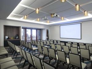 una sala de conferencias con sillas y una pantalla de proyección en The Cape, A Thompson Hotel, by Hyatt en Cabo San Lucas