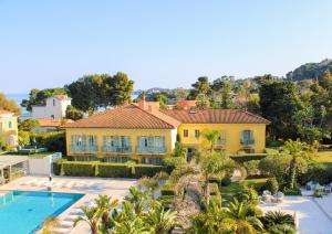 a large yellow house with a swimming pool and palm trees at Hotel Royal-Riviera in Saint-Jean-Cap-Ferrat