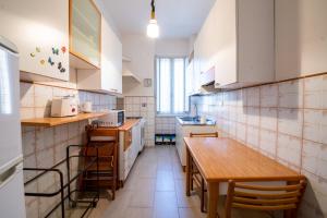 ローマにあるPiazza Carracciの白いキャビネットと木製テーブル付きのキッチン