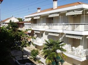 a large building with white balconies and a palm tree at Phaethon Apartments & Studios in Kallithea Halkidikis