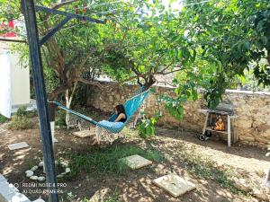 a woman sitting in a hammock under a tree at Family stone apartment in Kyparissia