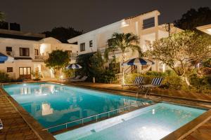 una piscina frente a una casa por la noche en Rainforest - Casa Azure 5 Min walk to the beach en Calangute