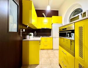 a yellow kitchen with yellow cabinets and a sink at K22 Filtrowa Apart Warsaw in Warsaw