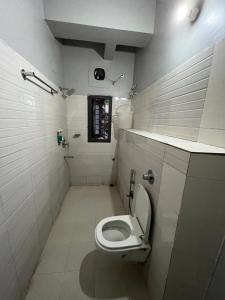 a white bathroom with a toilet and a window at Urban Inn Rukminigaon in Guwahati