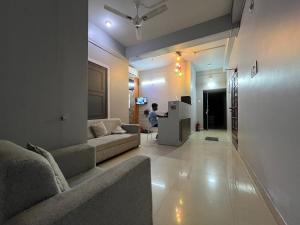 a living room with a couch and a person in the background at Urban Inn Rukminigaon in Guwahati