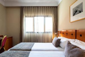 una camera d'albergo con letto e finestra di Petit Palace Arturo Soria Alcalá a Madrid