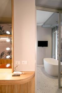 a bathroom with a large tub and a television at Hotel Luxor in Milano Marittima