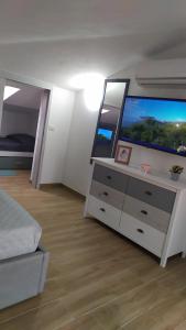 um quarto com uma cómoda e uma televisão de ecrã grande em L'ANCORA CASA AL MARE em Codaruina