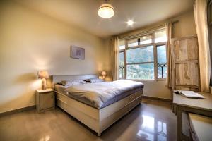 a bedroom with a bed and a window at NomadGao Dharamkot - Work-Friendly Comfort Stay With a View in McLeod Ganj