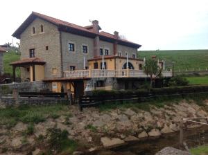 una casa grande en una colina junto a un río en Trisileja en Puente Romano en Toñanes