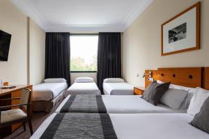 a hotel room with three beds and a desk at Petit Palace Arturo Soria Alcalá in Madrid