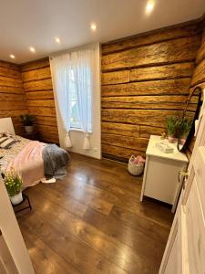 Schlafzimmer mit Holzwänden, einem Bett und einem Fenster in der Unterkunft Kreutzwaldi kodu in Võru