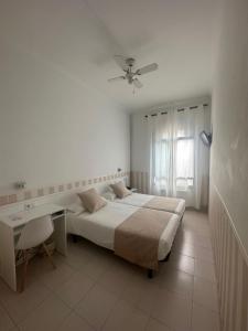 a bedroom with a bed and a desk and a window at Hotel Torino in Masnou