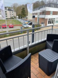 a balcony with two chairs and a view of a street at Ferienwohnungen Hüning in Grömitz