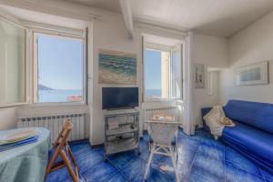 a room with a bed and a tv and two windows at Beach House Camogli in Camogli
