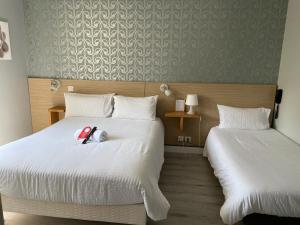 ビアリッツにあるホテル オクソのベッド2台、ベッドの上に動物の詰め物が備わるホテルルームです。