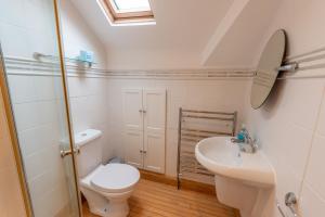 a white bathroom with a toilet and a sink at Dudley House in Woolacombe