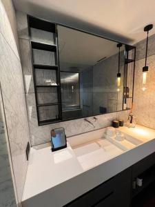een badkamer met een wastafel en een grote spiegel bij Luxury studio on Tlv w balcony on the sea in Jlil