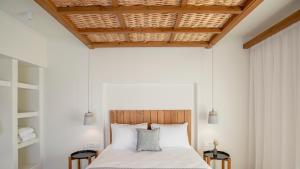 a bedroom with a bed with two tables at Kalami Suites in Livadi