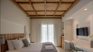 a bedroom with a large bed and a television at Kalami Suites in Livadi