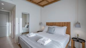 a bedroom with a large white bed with towels on it at Kalami Suites in Livadi