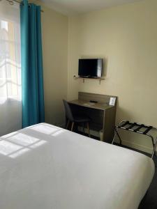 a room with a bed and a desk with a television at Le Vauban in Merville-Franceville-Plage