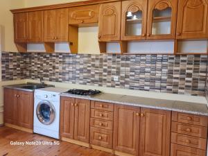 uma cozinha com armários de madeira e uma máquina de lavar roupa em Rose House em Sheki