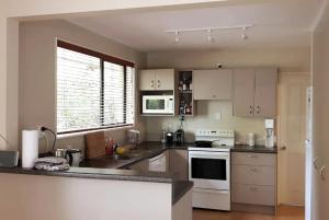 een keuken met witte apparatuur en een groot raam bij Highland Place Avonhead in Christchurch