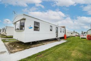 a white mobile home parked in a yard at 8 Berth Caravan At Highfield Grange In Essex Ref 26267e in Clacton-on-Sea