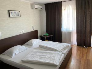 a bedroom with a bed with white sheets and a window at Pension La Ponton in Eşelniţa