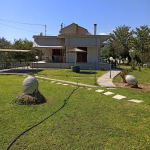 a house with a yard with two statues in the grass at Big garden house at Itea in Kírra