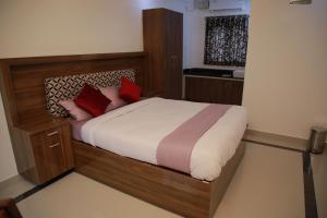 a bedroom with a wooden bed with red pillows at Kausthubhom Residency in Tiruvalla