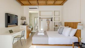 a bedroom with a bed and a desk and a television at Kalami Suites in Livadi