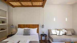 two beds in a room with white walls at Kalami Suites in Livadi