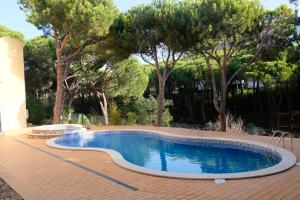 a large swimming pool with trees in the background at Praia Verde 130 in Castro Marim