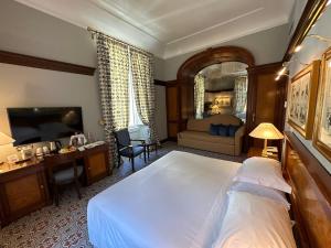 um quarto com uma grande cama branca e uma secretária em Hotel Albani Firenze em Florença