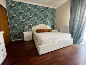 a bedroom with a white bed with a floral wallpaper at Anema & Core Home in Porto SantʼElpidio