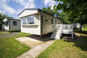 a tiny house in a yard with a porch at Caravan With Decking At Highfield Grange In Essex Ref 26452ba in Clacton-on-Sea