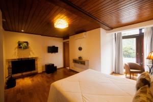 a bedroom with a white bed and a fireplace at Pousada Apple House - Campos do Jordao in Campos do Jordão